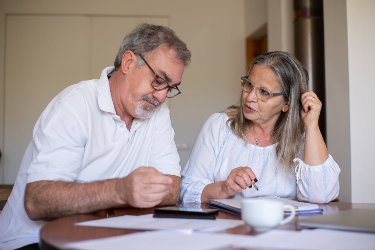 Senior couple reviewing documents and managing finances together at home, showing collaboration and care.